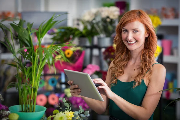 Lachende vrouw bloemist met behulp van digitale Tablet PC in de winkel van de bloemist — Stockfoto