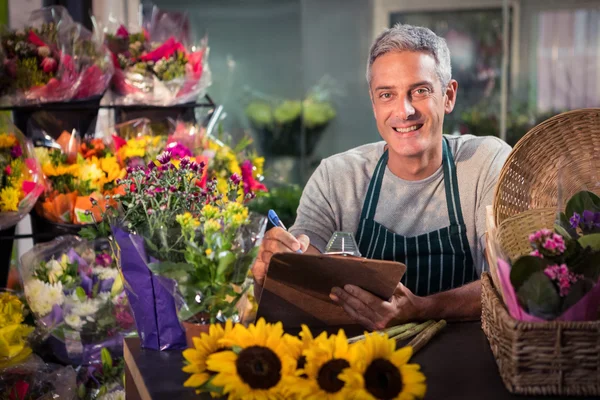 Floristería masculina escribiendo en portapapeles — Foto de Stock