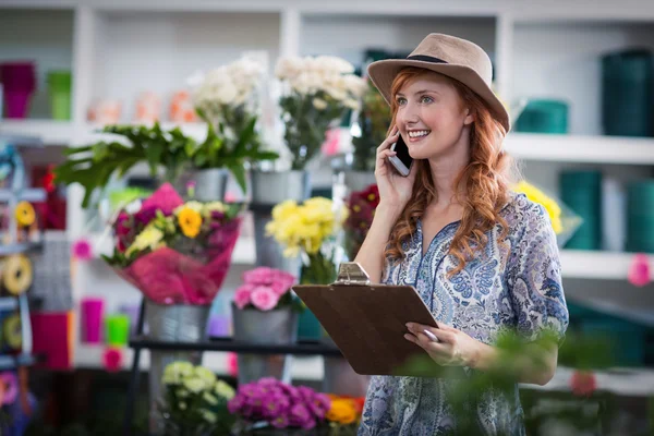 Vrouwelijke bloemist aannemen van order op mobiele telefoon — Stockfoto