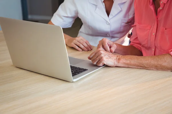 Pielęgniarka i starszy kobieta za pomocą laptopa — Zdjęcie stockowe
