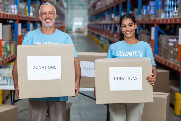 Voluntarios sonríen y sostienen cajas de donaciones — Foto de Stock