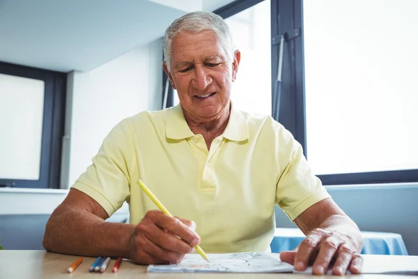 Hombre mayor usando un libro para colorear — Foto de Stock