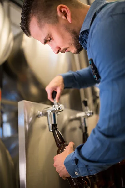 Cervejeiro enchendo cerveja em garrafa — Fotografia de Stock