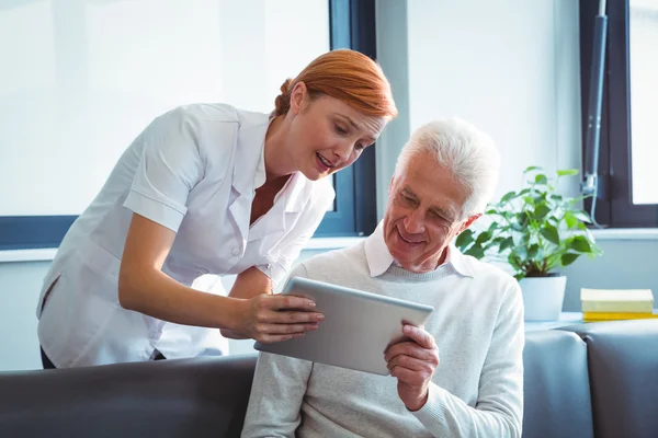 Sjuksköterska och senior man använder en digital tablet — Stockfoto