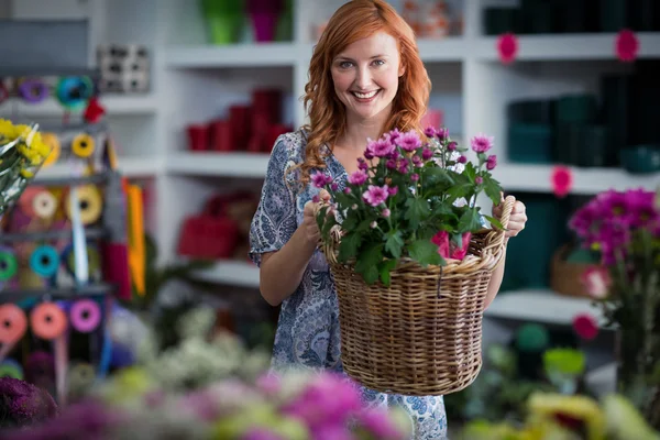 Щасливий жіночий флорист тримає кошик квітів — стокове фото