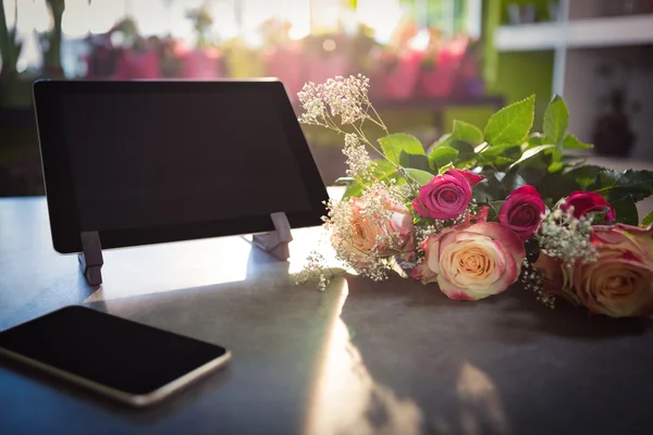 Çiçek buketi smartphone ve masanın üzerine dijital tablet ile — Stok fotoğraf