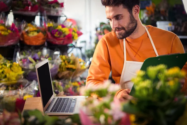 Floristería masculina comprobando orden en laptop —  Fotos de Stock