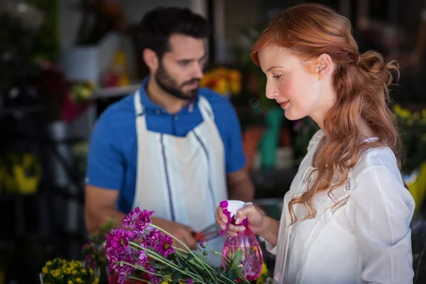 Mujer rociando agua sobre un ramo de flores —  Fotos de Stock