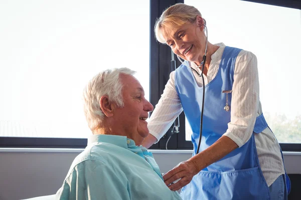 Sjuksköterska med stetoskop för att ta hand om en äldre man — Stockfoto