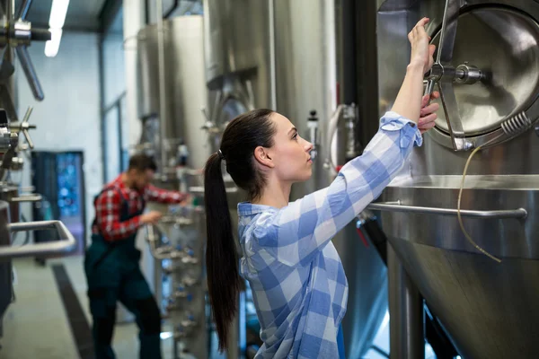 Trabalhadora de manutenção feminina examinando máquina de cervejaria — Fotografia de Stock