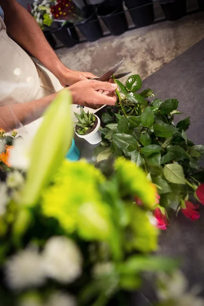 Blumenhändler schneidet Stiele von Blumen im Blumenladen — Stockfoto