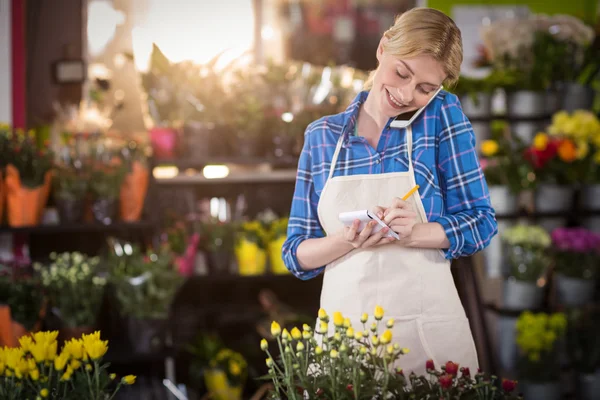 Female florist taking an order on mobile phone — Stock Photo, Image