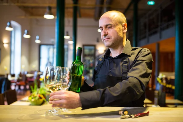 Servitören hålla glasögon och en flaska vitt vin — Stockfoto
