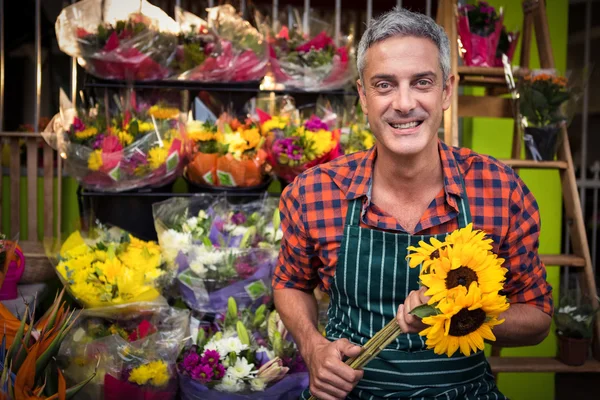 Florista masculino segurando monte de flores na loja de flores — Fotografia de Stock