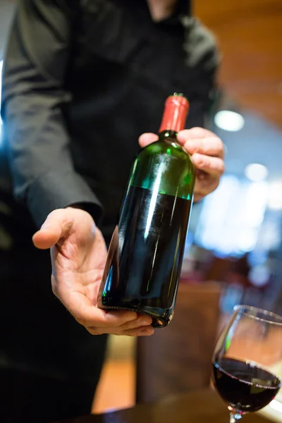 Camarero sosteniendo una botella de vino tinto —  Fotos de Stock