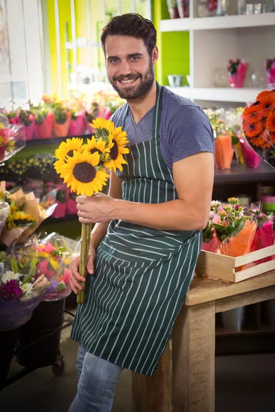 Florista masculino segurando um monte de flores em sua loja de flores — Fotografia de Stock