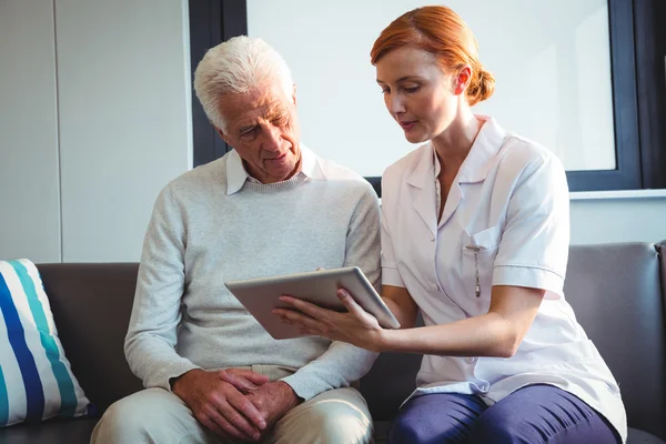 Sjuksköterska och senior man använder en digital tablet — Stockfoto