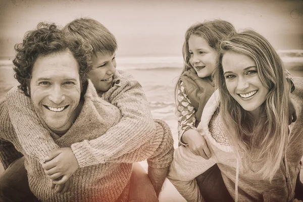 Lyckliga paret åker snålskjuts barnen på stranden — Stockfoto