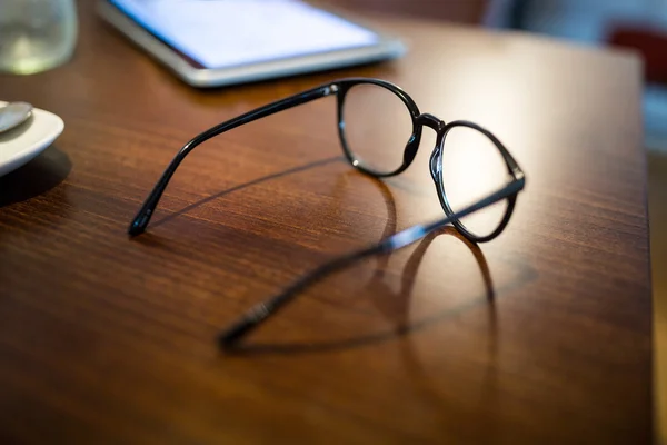 Gözlük ve ahşap masa üstünde hareket eden telefon — Stok fotoğraf