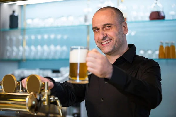 Portrait of bar tender offering beer — Stock Photo, Image