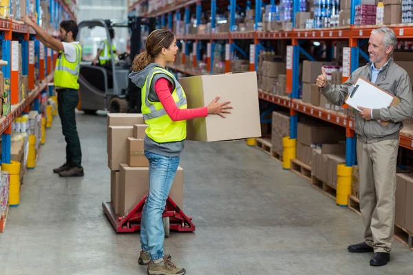 Manager looking a worker holding cardboard boxes with thumbs up — Stock Photo, Image