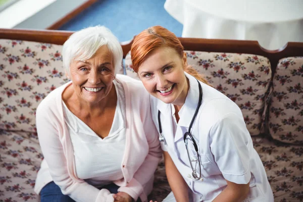 Senior vrouw en verpleegkundige glimlachend op camera — Stockfoto