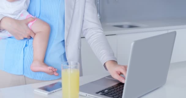 Mutter benutzt Laptop während sie Baby hält — Stockvideo