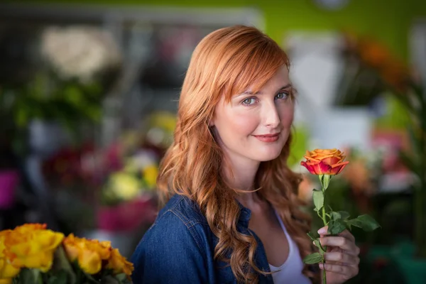 Kvinnliga florist innehar en rosa blomma — Stockfoto