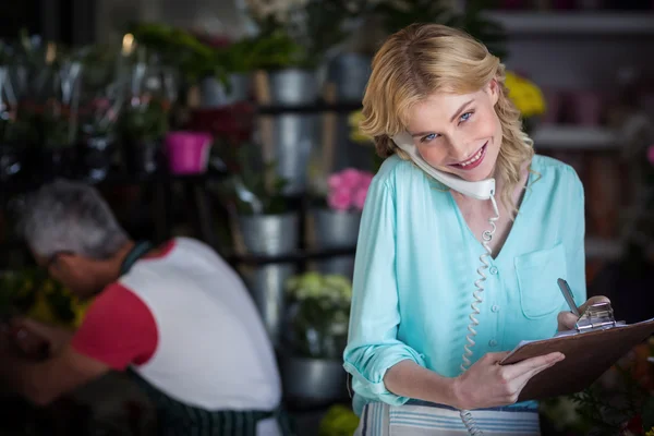 Leende kvinna florist med en beställning på telefon — Stockfoto