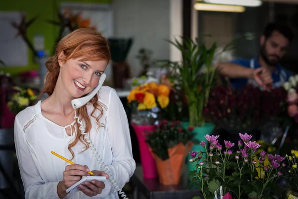 Floristería femenina tomando un pedido por teléfono —  Fotos de Stock