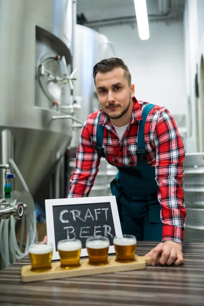 Brasseur avec quatre verres de bière artisanale sur table — Photo