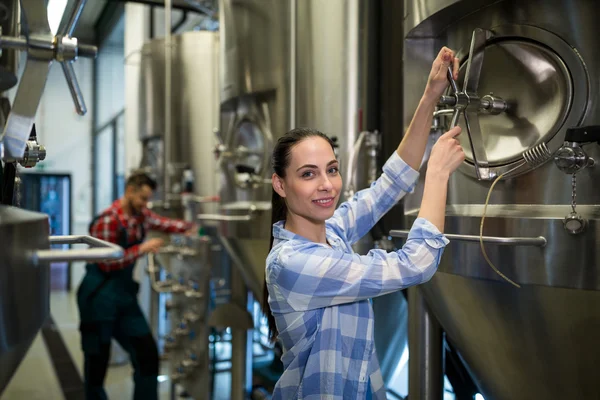 Vrouwelijke onderhoud werknemer onderzoeken brouwerij machine — Stockfoto