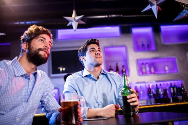 Vänner sitter vid bardisken och med öl — Stockfoto