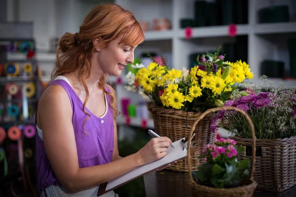 女性写作在剪贴板上的花店 — 图库照片