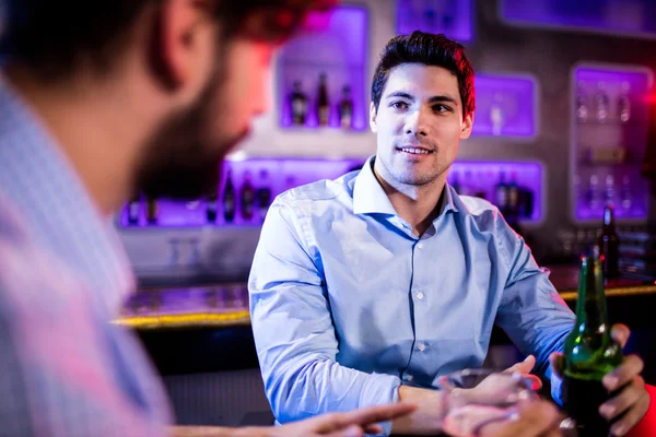 Amigos interagindo uns com os outros no balcão do bar — Fotografia de Stock