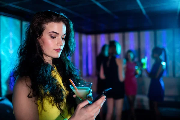 Жінка вводить текстове повідомлення, маючи коктейль — стокове фото