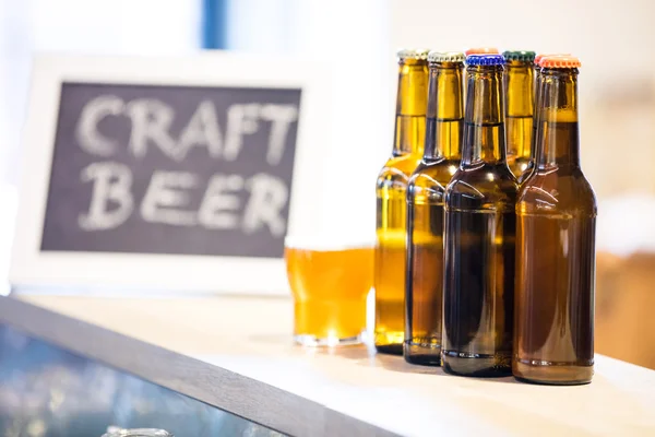 Vasos de cerveza y botellas en el mostrador de la barra — Foto de Stock