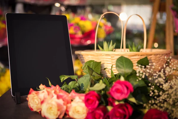 Bando de rosas e tablet digital na mesa — Fotografia de Stock