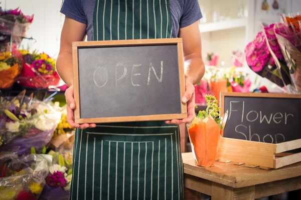 Manliga florist med öppen skylt på skiffer på hans blomsteraffär — Stockfoto