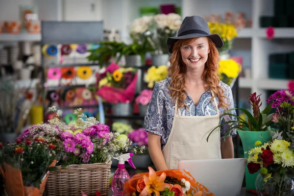 Fiorista sorridente utilizzando il computer portatile nel negozio di fiori — Foto Stock