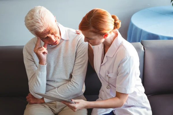 Sjuksköterska och senior man använder en digital tablet — Stockfoto
