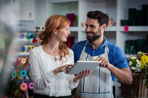 Pareja usando la tableta digital y mirándose entre sí —  Fotos de Stock