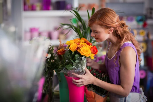 Vrouwelijke bloemist ruikende bloemboeket — Stockfoto