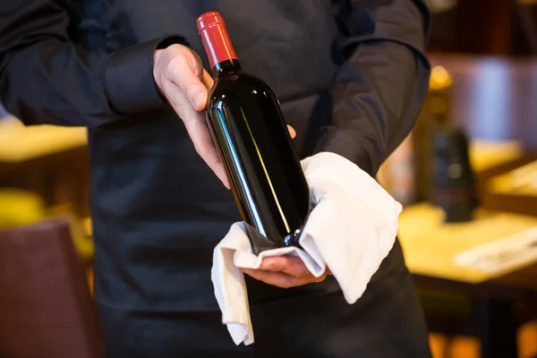 Waiter holding a bottle of red wine — Stock Photo, Image