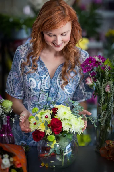 Floristería femenina revisando un arreglo de flores en jarrón —  Fotos de Stock