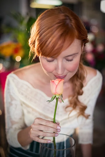 Female florist smelling a rose flower — Stock Photo, Image