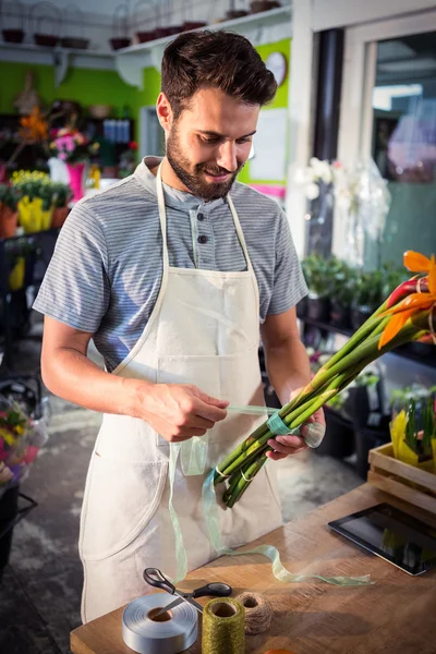 Чоловічий флорист зав'язує поліетиленову стрічку на букет квітів — стокове фото