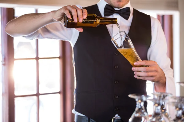 Seção intermediária do barman derramando uma cerveja em um copo — Fotografia de Stock