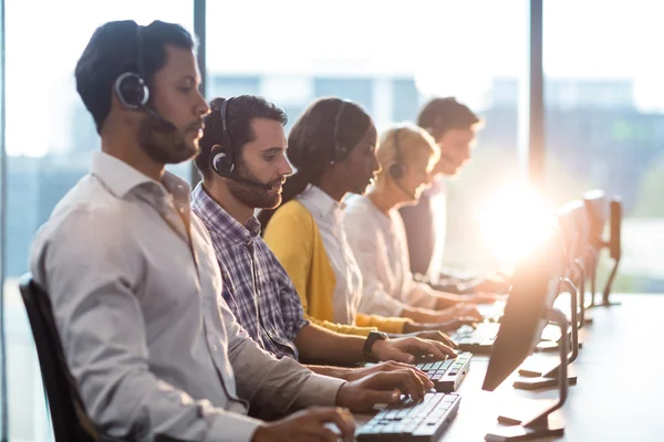 Équipe de collègues travaillant à leur bureau avec casque — Photo