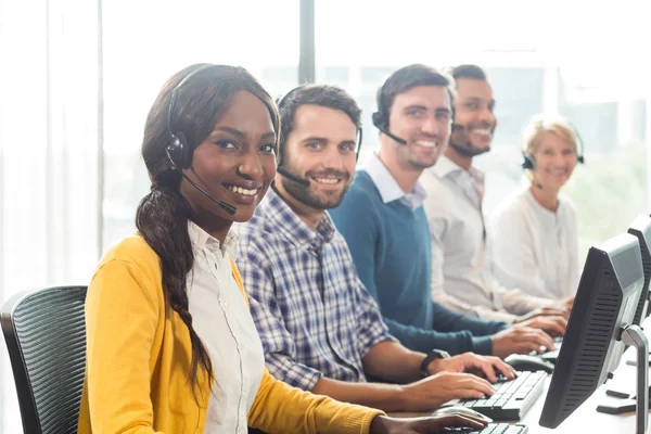 Team av kollegor som arbetar på sitt skrivbord med headset — Stockfoto